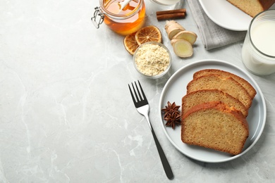 Slices of delicious gingerbread cake served with milk on light grey table, flat lay. Space for text