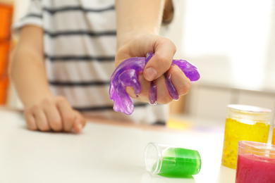Photo of Little boy playing with slime at table indoors, closeup