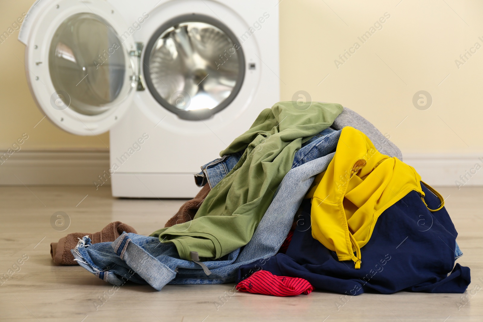 Photo of Pile of dirty laundry near washing machine indoors