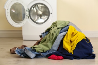 Pile of dirty laundry near washing machine indoors