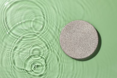 Photo of Presentation of product. Stone podium in water on green background, top view. Space for text