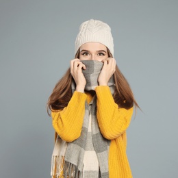 Photo of Happy young woman in warm clothes on grey background. Winter season