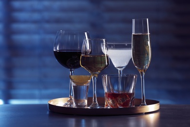 Photo of Tray with different alcohol drinks on table indoors