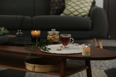 Photo of Tea, cookies and decorative elements on wooden table in living room