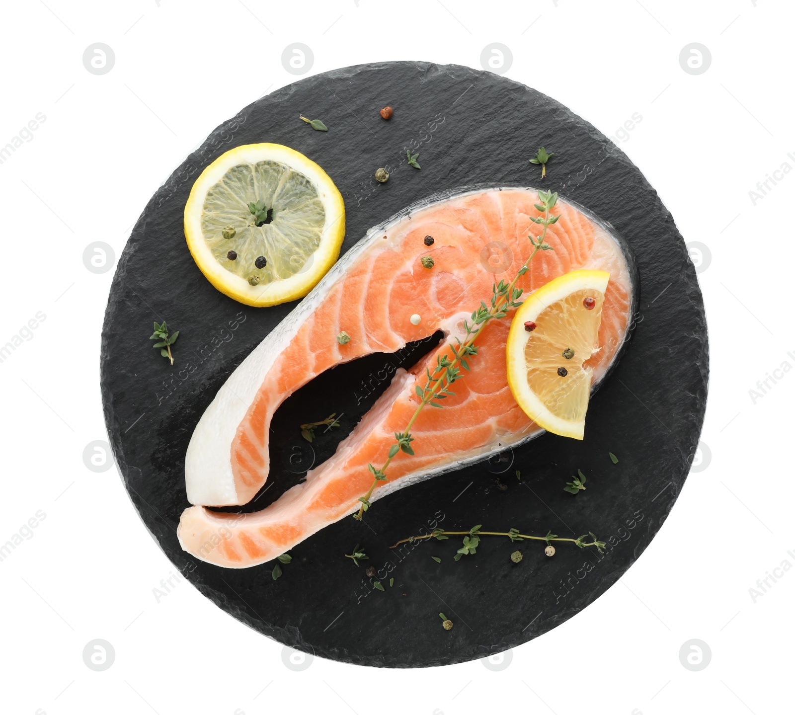 Photo of Slate plate with fresh salmon steak and lemon on white background, top view