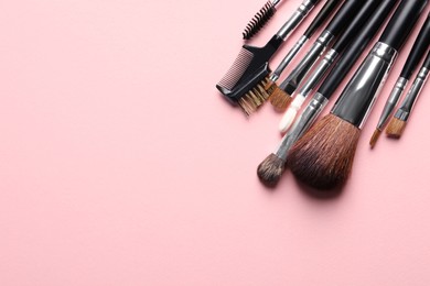 Photo of Different makeup brushes on pink background, flat lay. Space for text