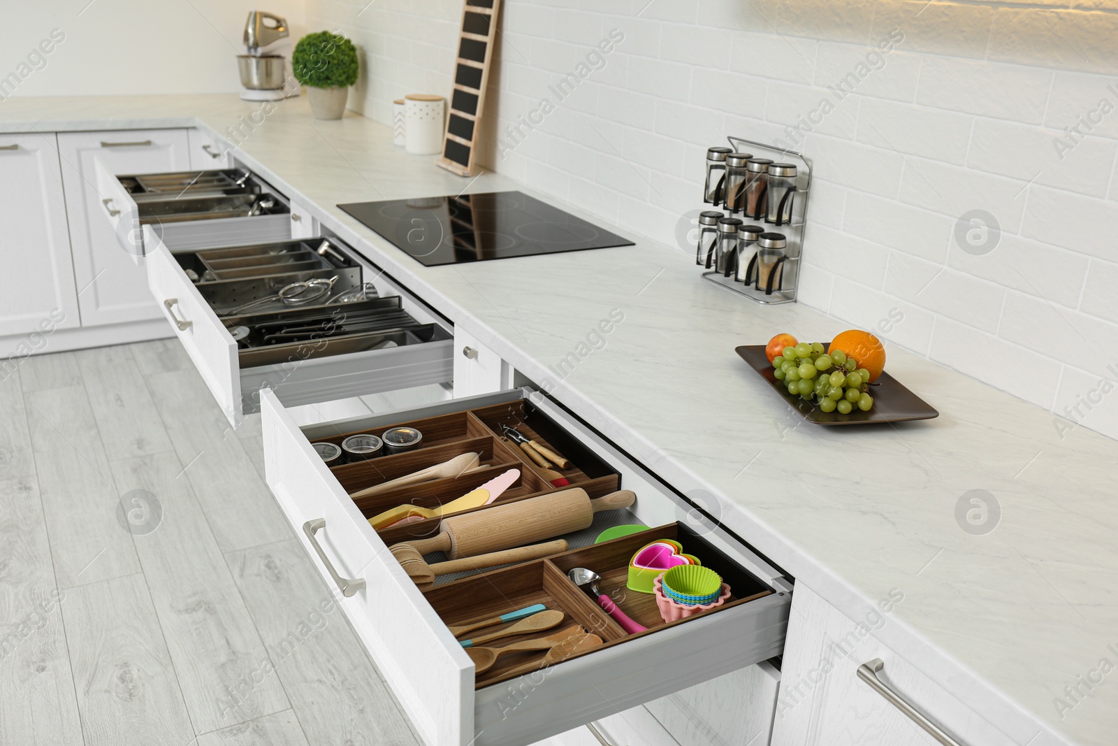 Photo of Open drawers with different utensils in kitchen