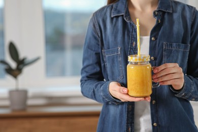 Woman with delicious smoothie at home, closeup. Space for text