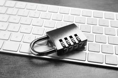Cyber security. Metal combination padlock and keyboard on grey table, closeup