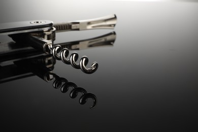 Photo of One corkscrew (sommelier knife) on mirror surface, closeup. Space for text