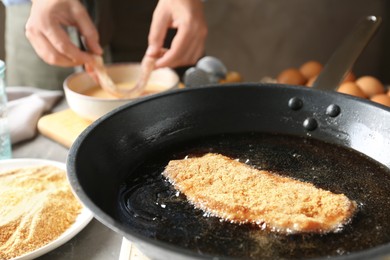 Photo of Woman cooking schnitzel at table, selective focus