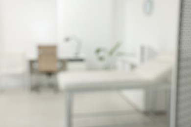 Blurred view of modern medical office with doctor's workplace and examination table in clinic