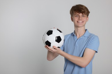 Photo of Teenage boy with soccer ball on light grey background. Space for text