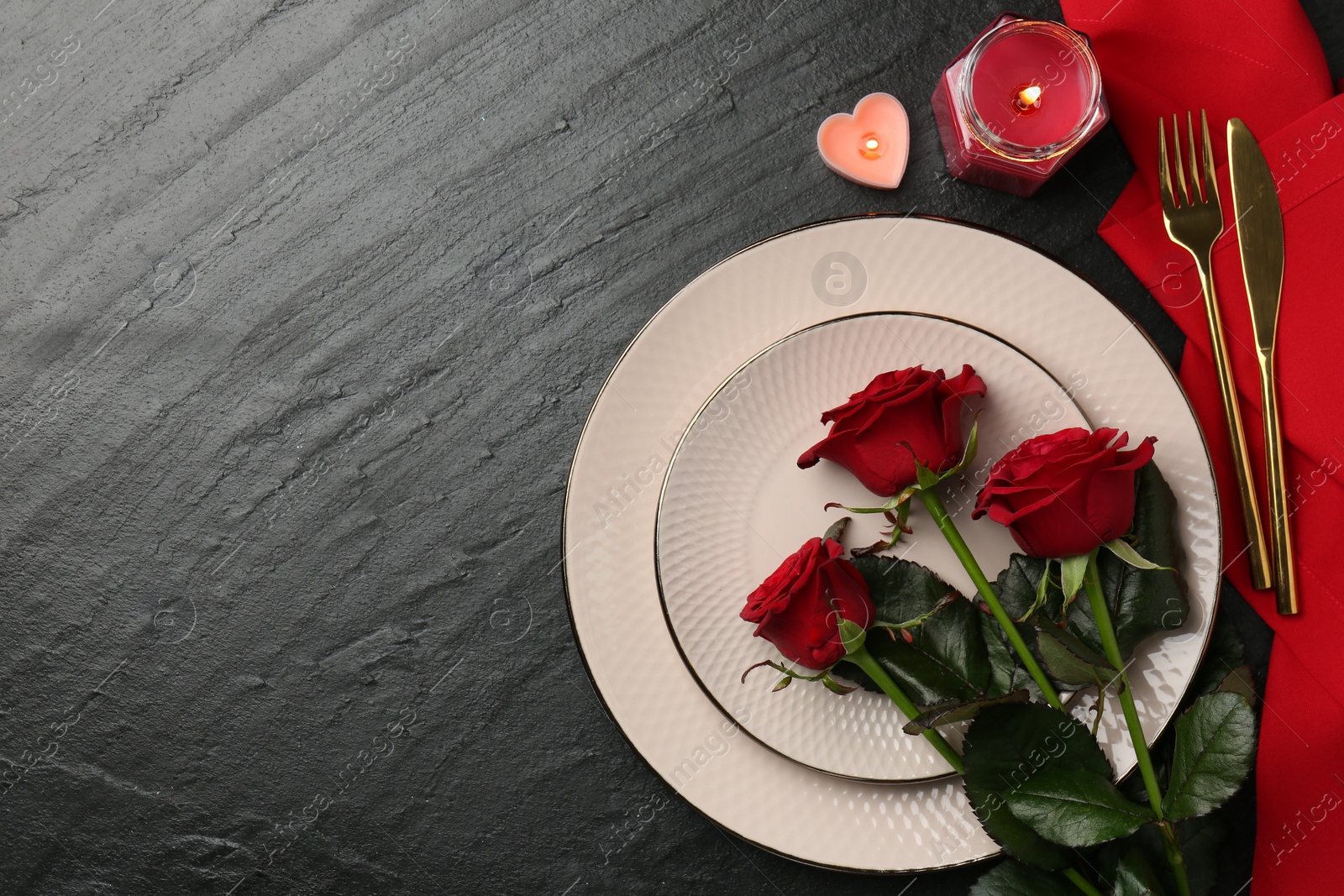 Photo of Place setting with candles and roses for romantic dinner on grey textured table, flat lay. Space for text