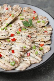 Photo of Tasty pickled anchovies with spices on grey textured table, closeup