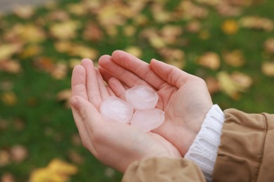 Woman holding hail grains after thunderstorm outdoors, closeup