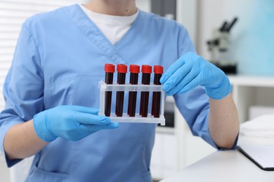 Laboratory testing. Doctor with blood samples in tubes at hospital, closeup