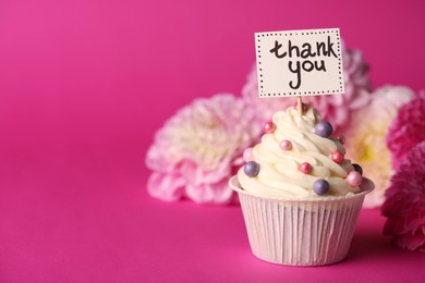 Tasty cupcake with Thank You note and dahlias on pink background, space for text
