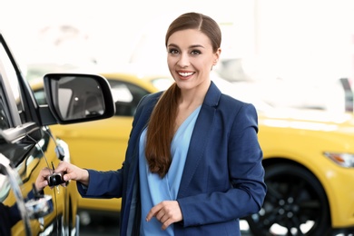 Young woman standing near new car in salon