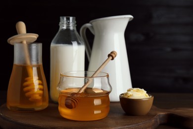 Jars with tasty honey, milk and butter on wooden table
