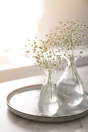 Vases with gypsophila flowers on table in kitchen. Interior design