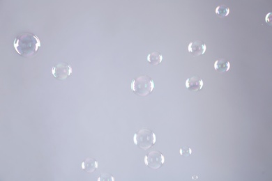 Photo of Beautiful translucent soap bubbles on grey background
