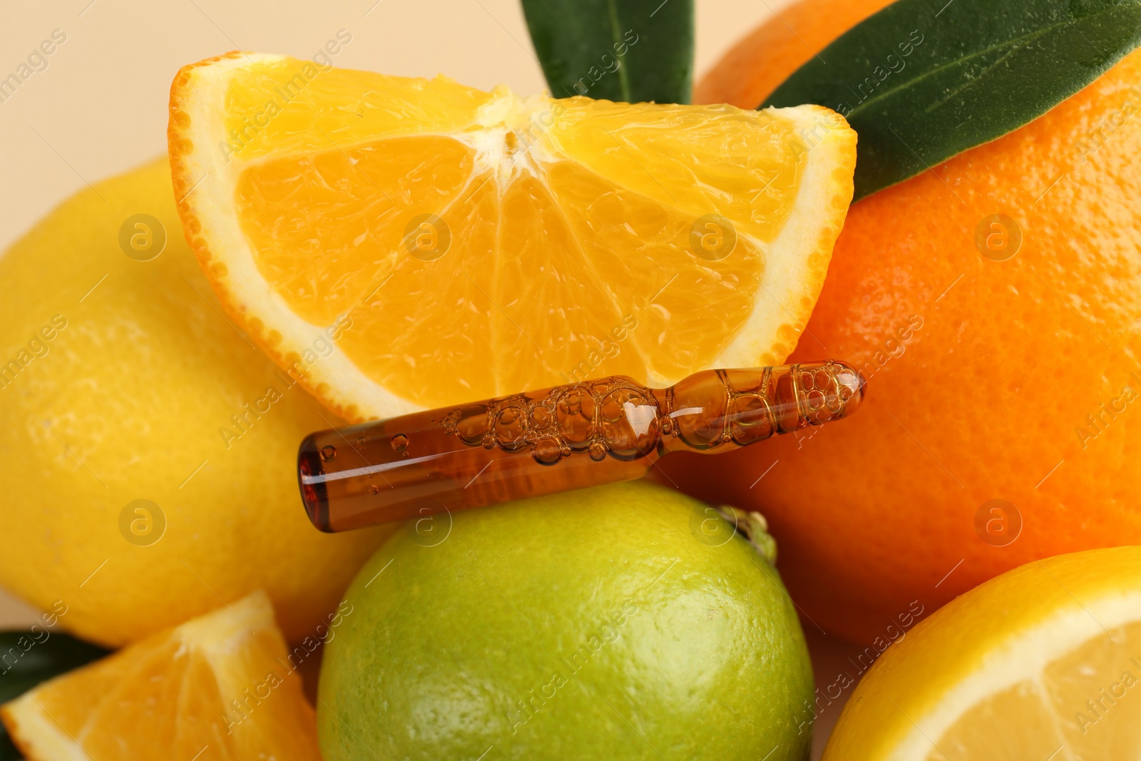 Photo of Skincare ampoule with vitamin C, different citrus fruits and leaves on beige background, closeup