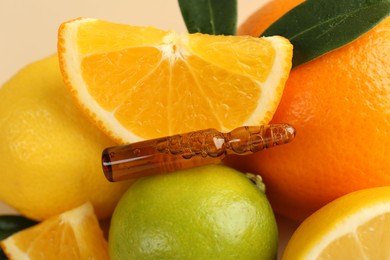 Skincare ampoule with vitamin C, different citrus fruits and leaves on beige background, closeup