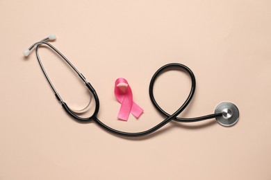 Photo of Pink ribbon and stethoscope on beige background, flat lay. Breast cancer awareness