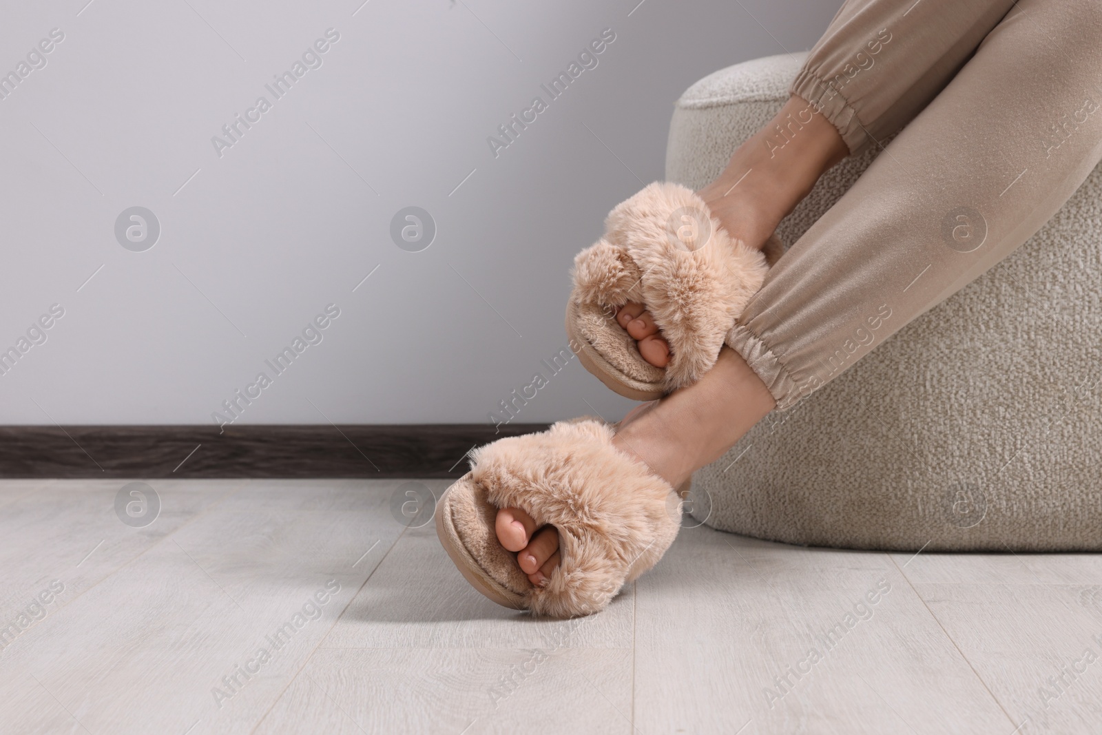 Photo of Woman wearing beige soft slippers indoors, closeup. Space for text