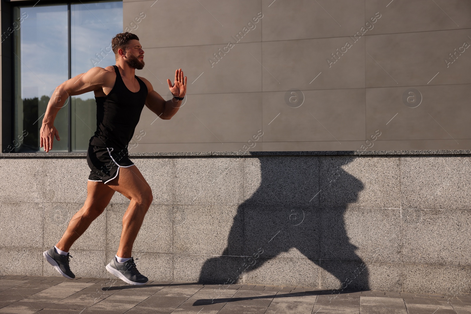 Photo of Young man running near building outdoors. Space for text