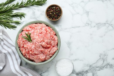 Photo of Bowl of raw fresh minced meat with rosemary and spices on white marble table, flat lay. Space for text