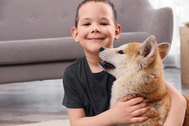 Photo of Happy boy with Akita Inu dog indoors. Lovely friends