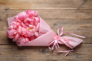 Photo of Beautiful bouquet of pink peonies on wooden table, top view