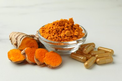Photo of Aromatic turmeric powder, pills and raw root on white marble table, closeup