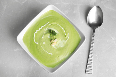 Delicious broccoli cream soup served on grey marble table, flat lay