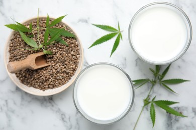 Photo of Hemp milk, seeds and fresh leaves on white marble table, flat lay