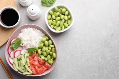 Photo of Poke bowl with salmon, edamame beans and vegetables on light grey table, flat lay. Space for text
