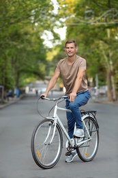 Photo of Handsome man riding bicycle outdoors on summer day