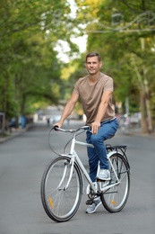 Handsome man riding bicycle outdoors on summer day