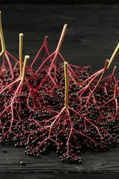 Photo of Bunches of ripe elderberries (Sambucus) on black wooden table, closeup