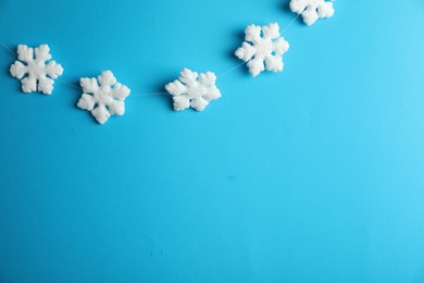 Beautiful decorative snowflakes hanging on light blue background, space for text