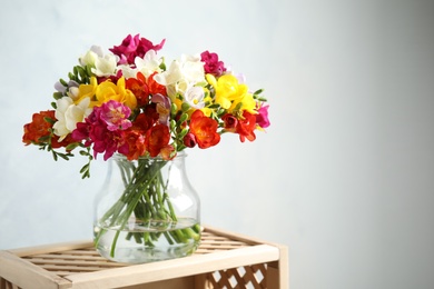 Bouquet of spring freesia flowers in vase on light background. Space for text