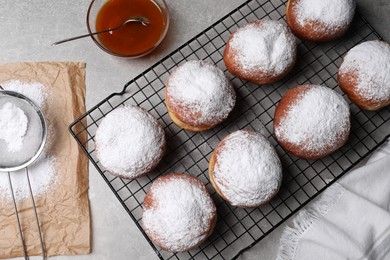 Delicious sweet buns with powdered sugar, jam and strainer on gray table, flat lay