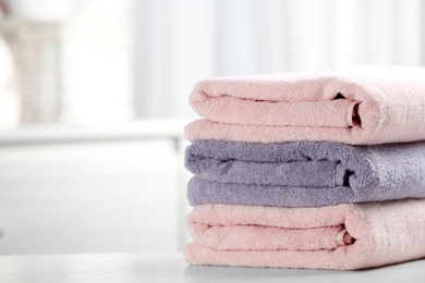 Photo of Stack of fresh towels on table. Space for text