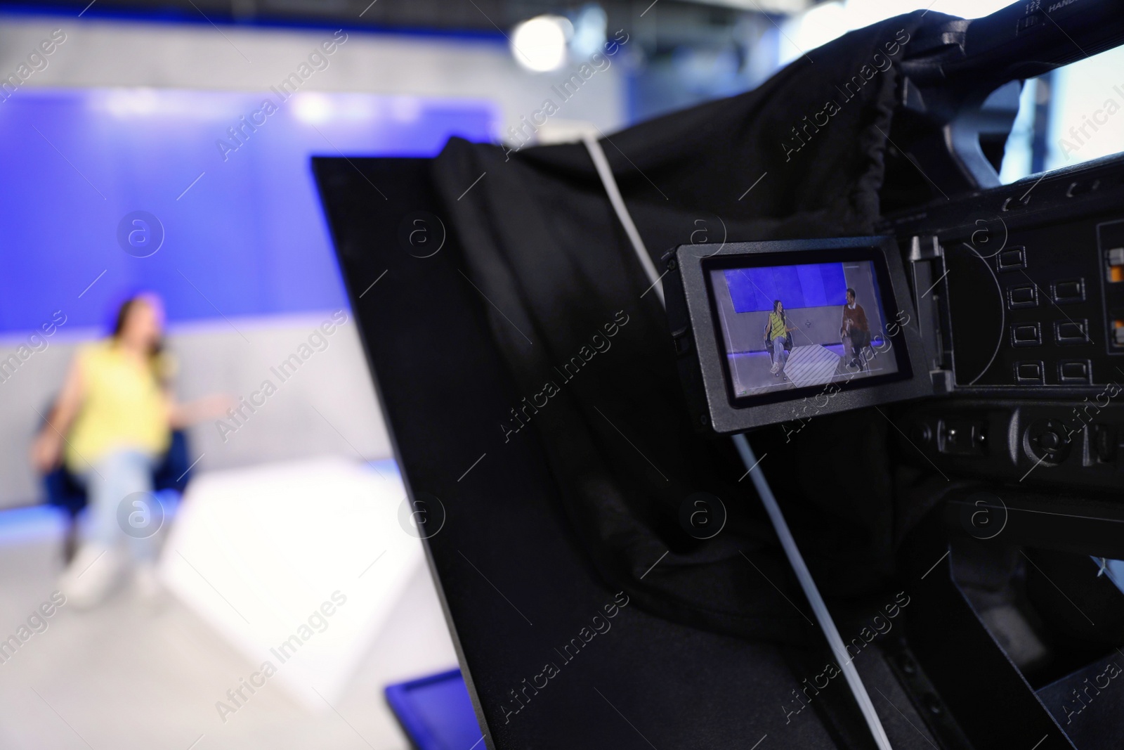 Photo of Presenters working in studio, focus on video camera screen