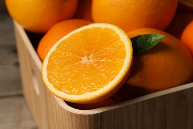 Many whole and cut ripe oranges on wooden table, closeup