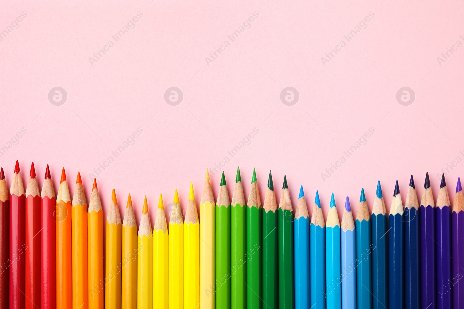 Photo of Flat lay composition with color pencils on pink background. Space for text