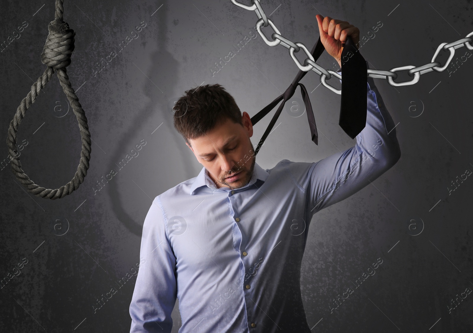 Image of Depressed businessman holding tie like noose against grey background