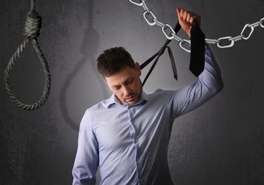 Image of Depressed businessman holding tie like noose against grey background
